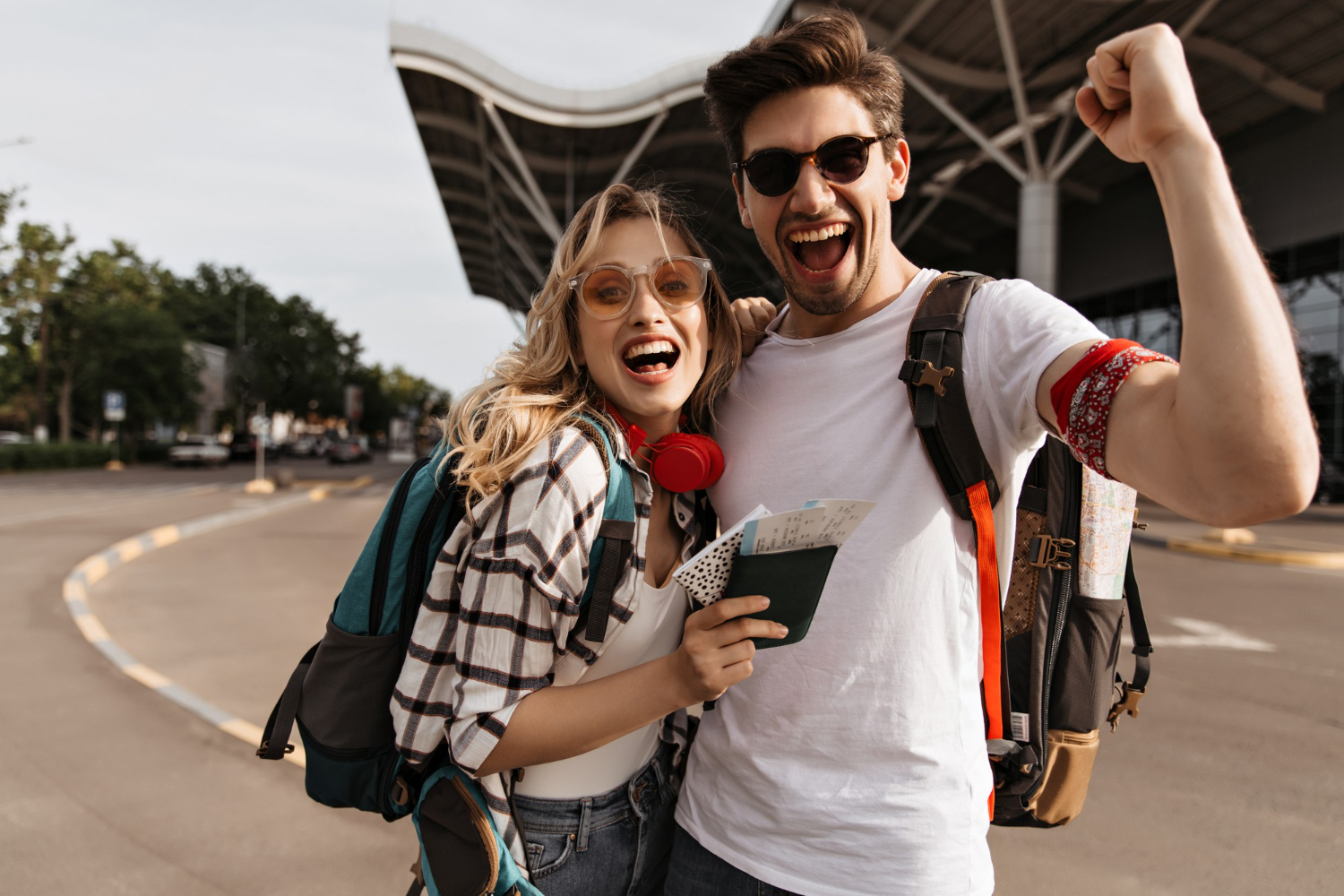 attractive blonde woman sunglasses man white tee smiles takes selfie near airport